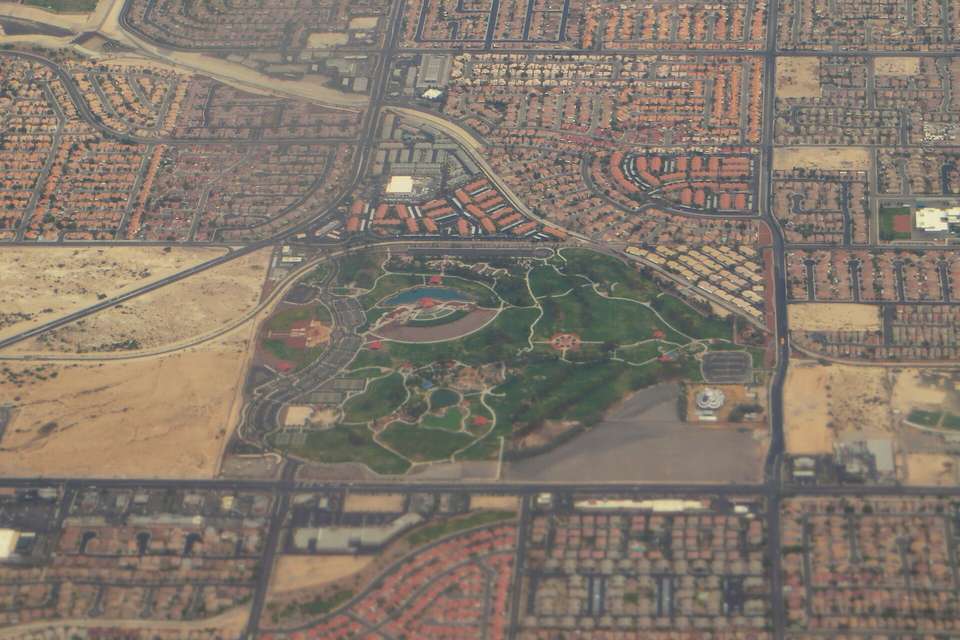 Aerial view of a large green park surrounded by grids of desert subdivisions and open lots