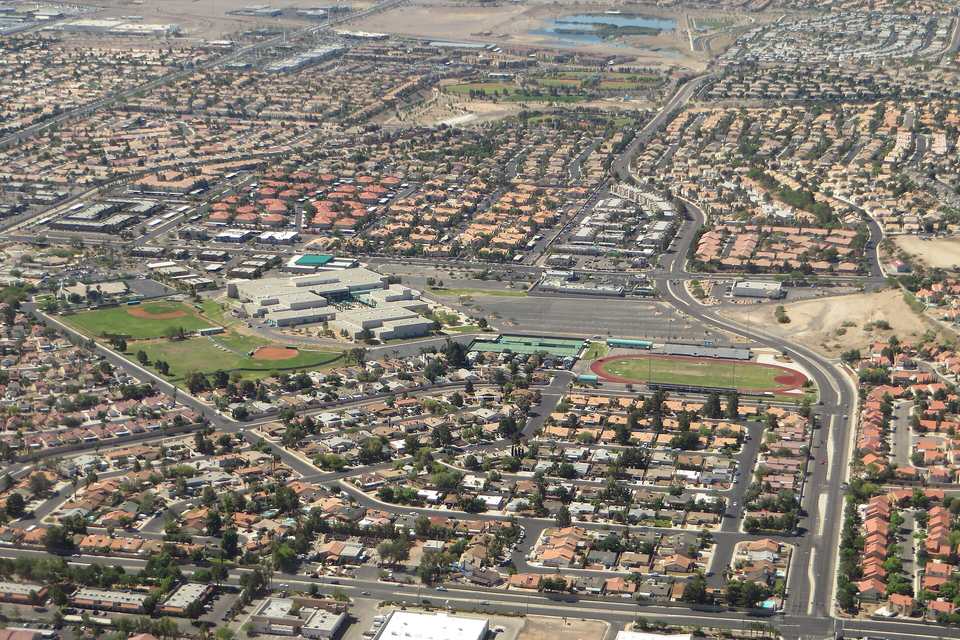 Aerial view of Henderson neighborhoods with tile roofs, a high school campus with ball fields and a running track