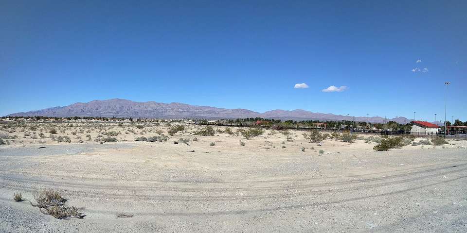 Wide view across open desert to a long mountain range under a clear blue sky, North Las Vegas